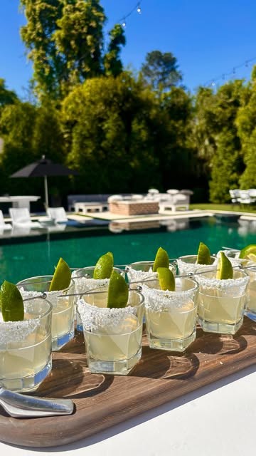 Rows of salted margaritas on a board beside a pool