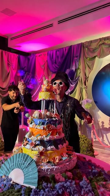 A tiered celebration cake under pink light at an event designed by April